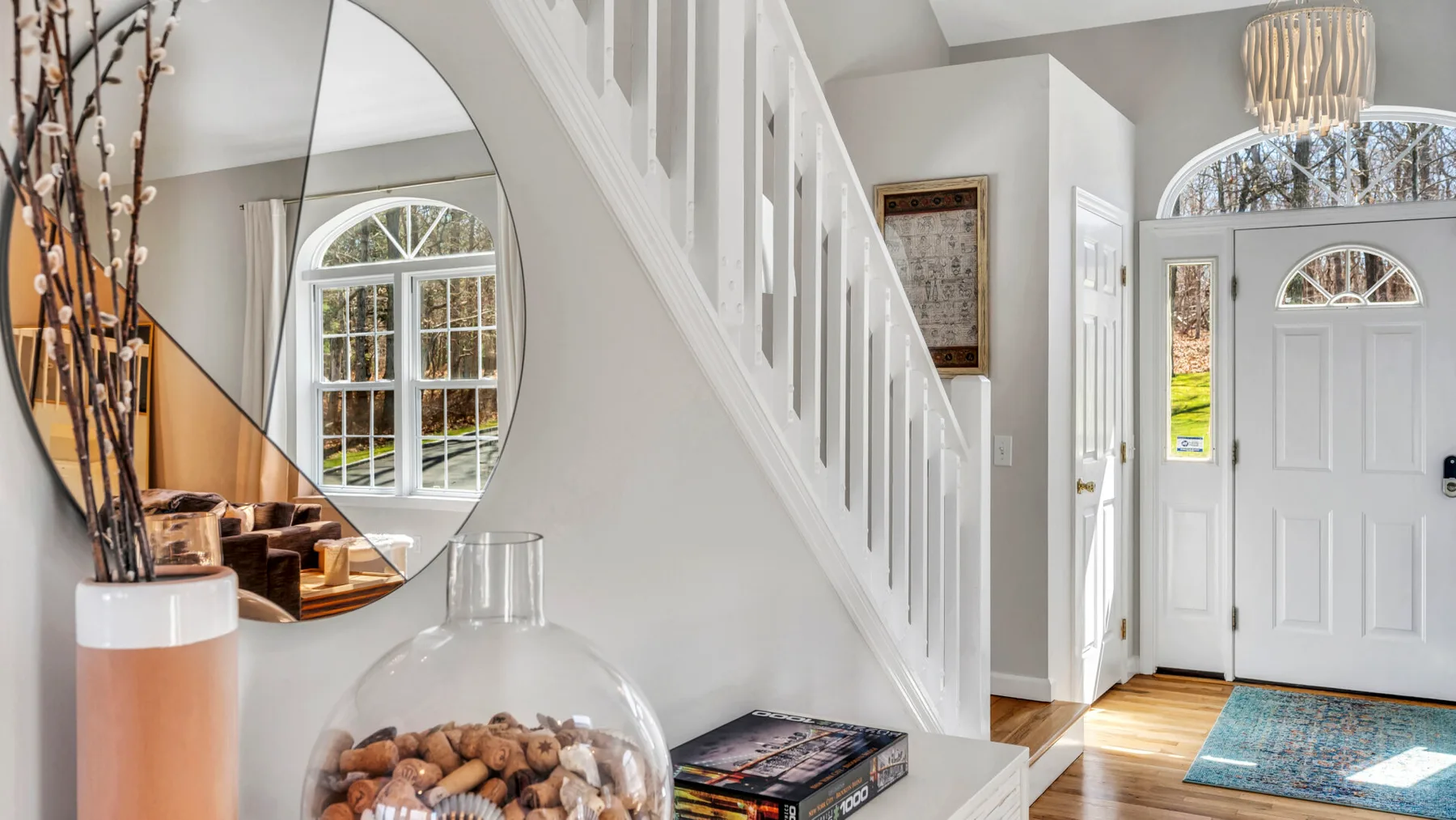 A bright entryway features a white front door and a staircase.