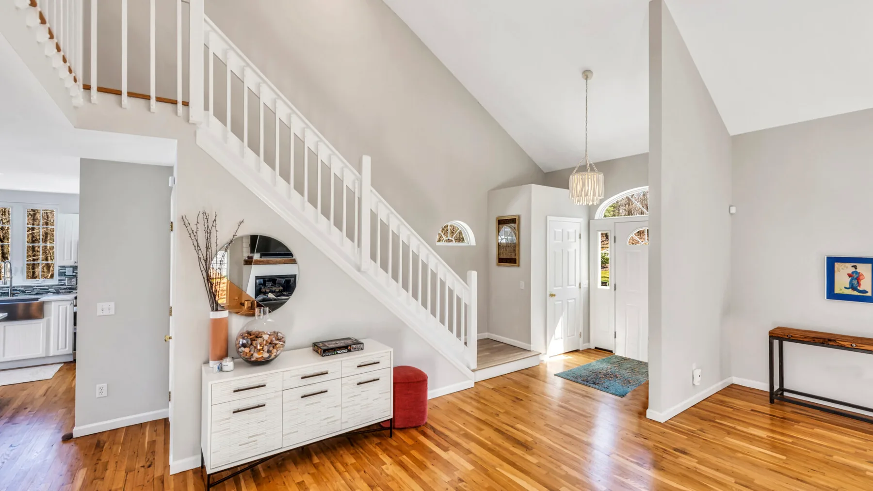 An open entry hall with a staircase, wood flooring, and a console table.