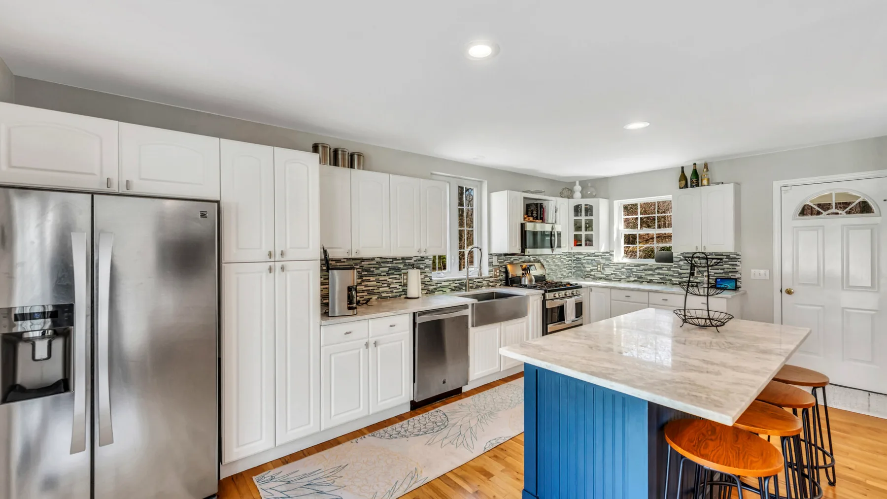 A bright kitchen with white cabinetry, stainless steel appliances, and a central island.
