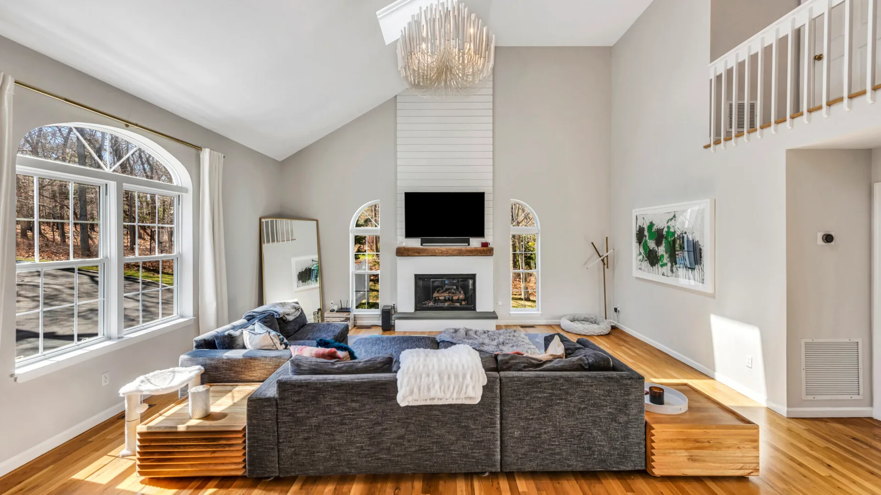A bright living room with seating arranged around a fireplace and television.