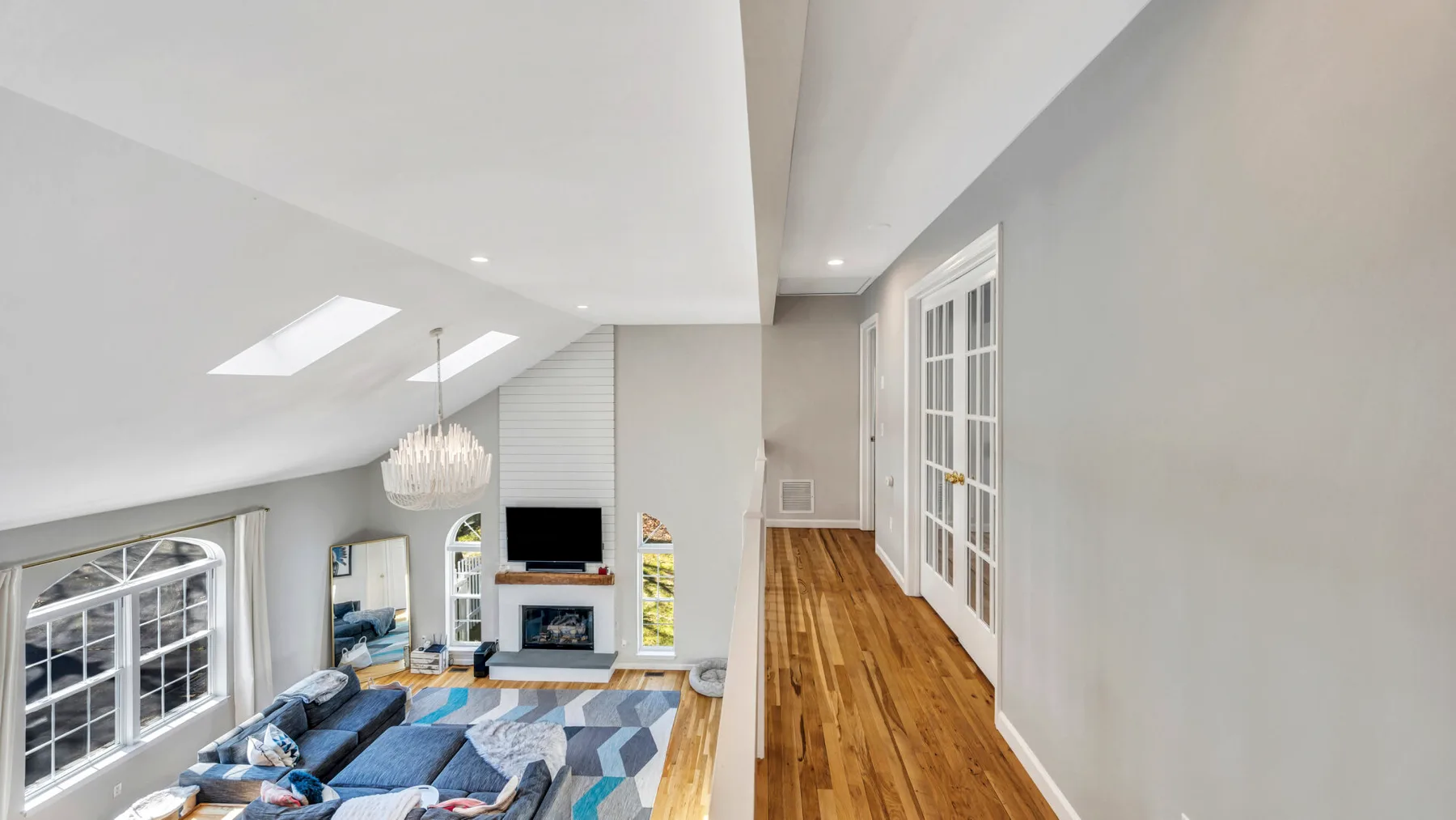 A bright living room with blue seating beneath a sloped ceiling.