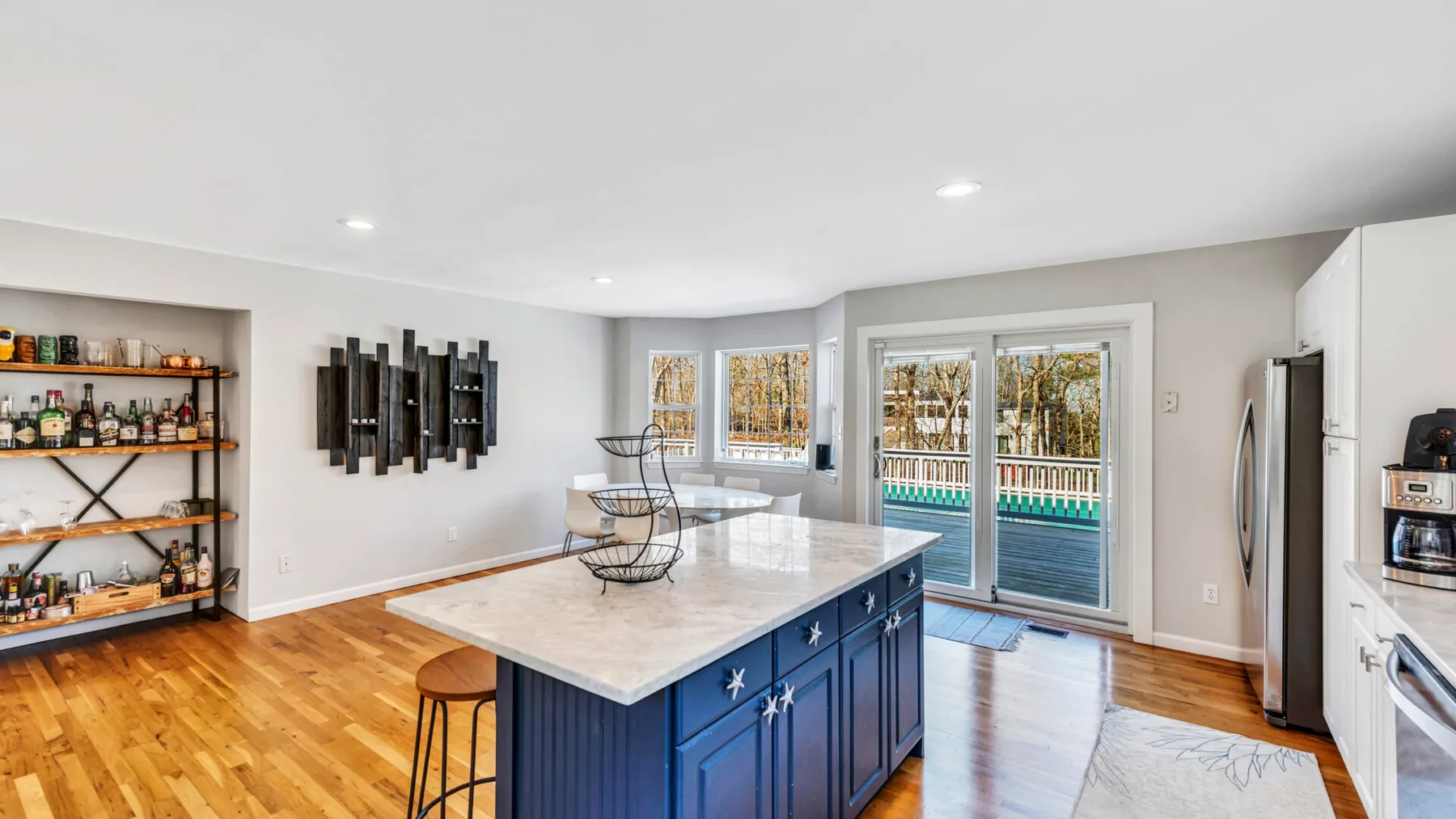 A bright kitchen with a blue island and glass doors opening onto a patio.
