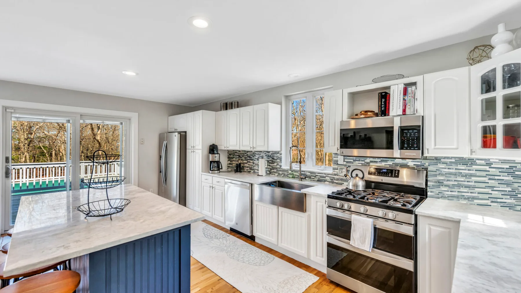 A bright kitchen with white cabinetry, stainless steel appliances, and an island.