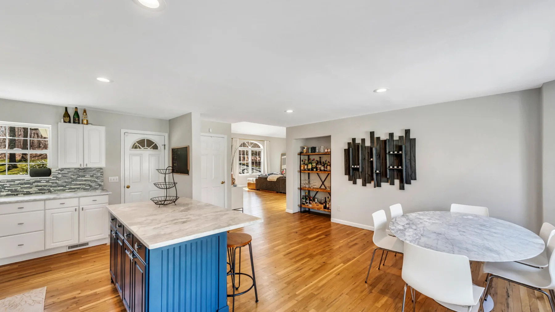 Bright open-plan kitchen and dining area with a blue island and round table.