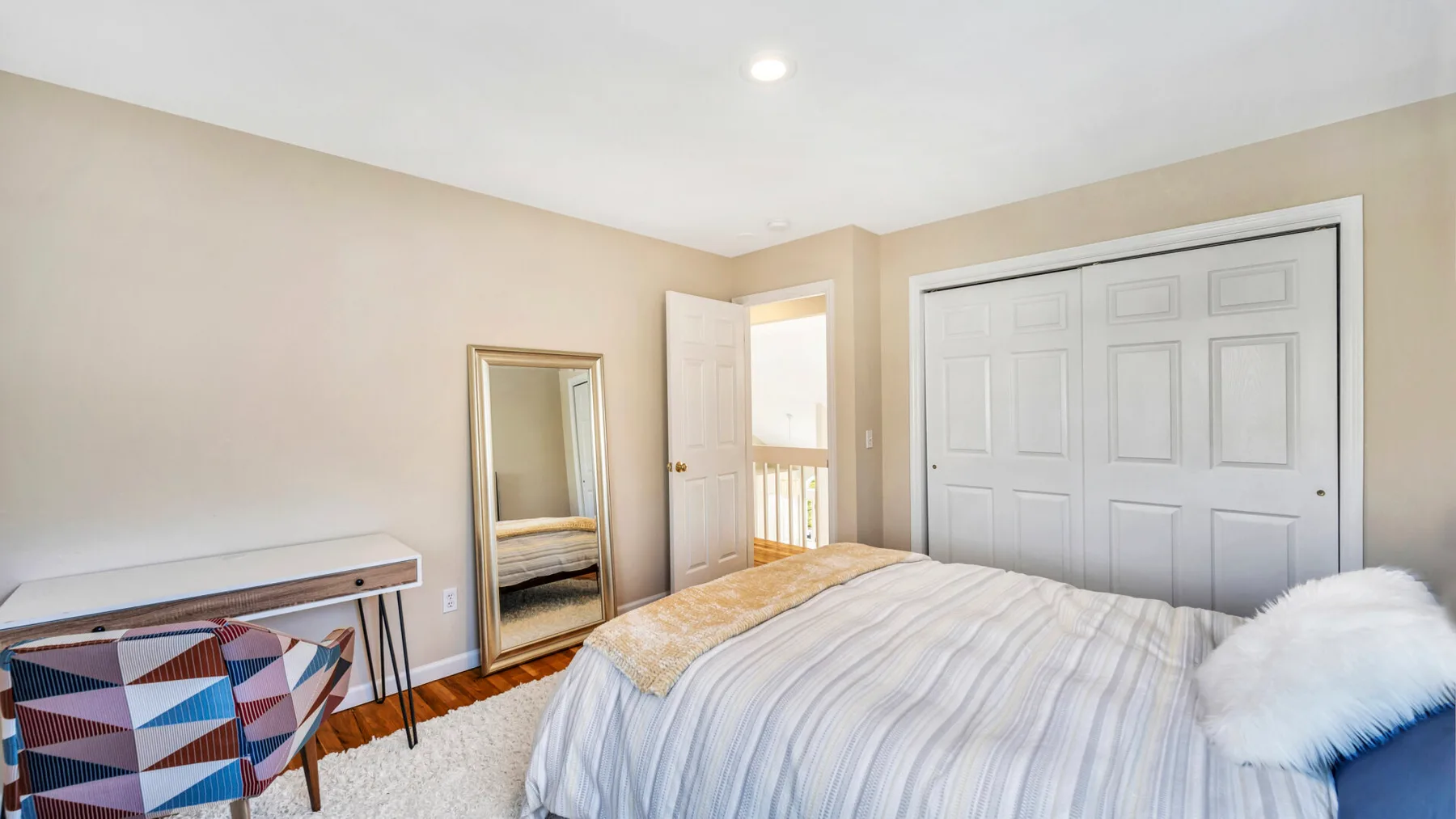 A bedroom with a bed, a mirror, and an open doorway.