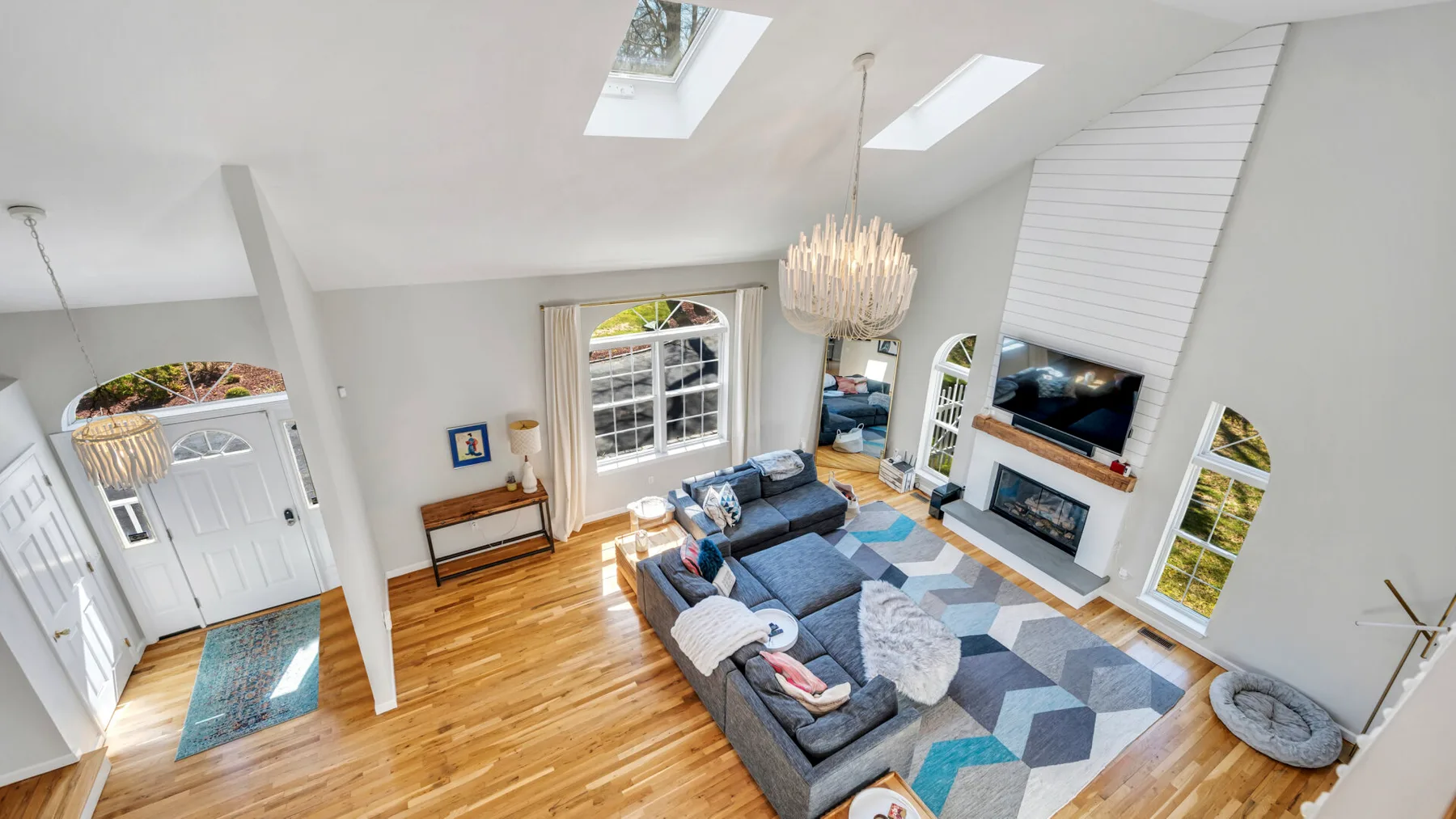 A bright living room with seating arranged around a fireplace and television.