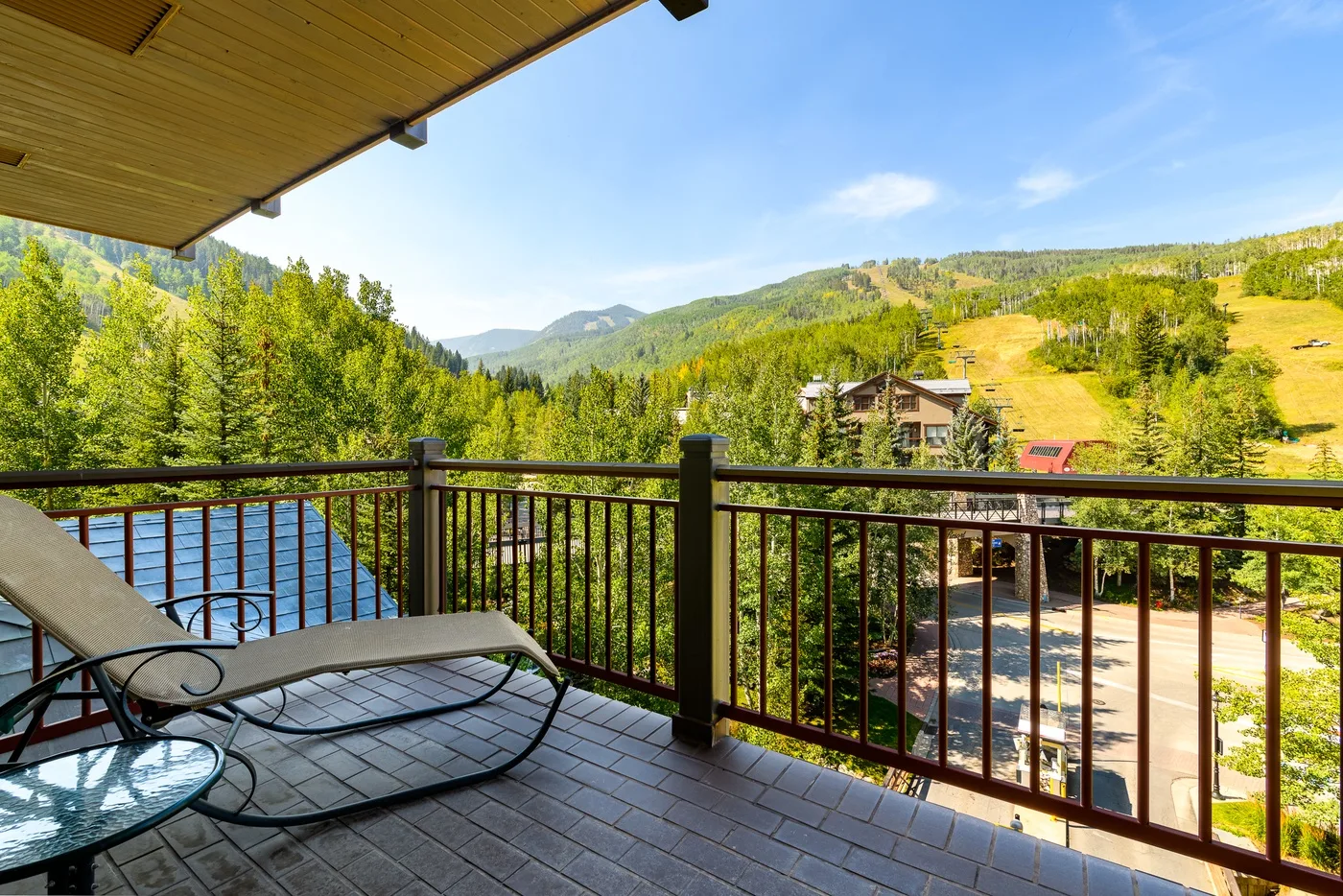 A balcony overlooks a river and green mountain slopes.