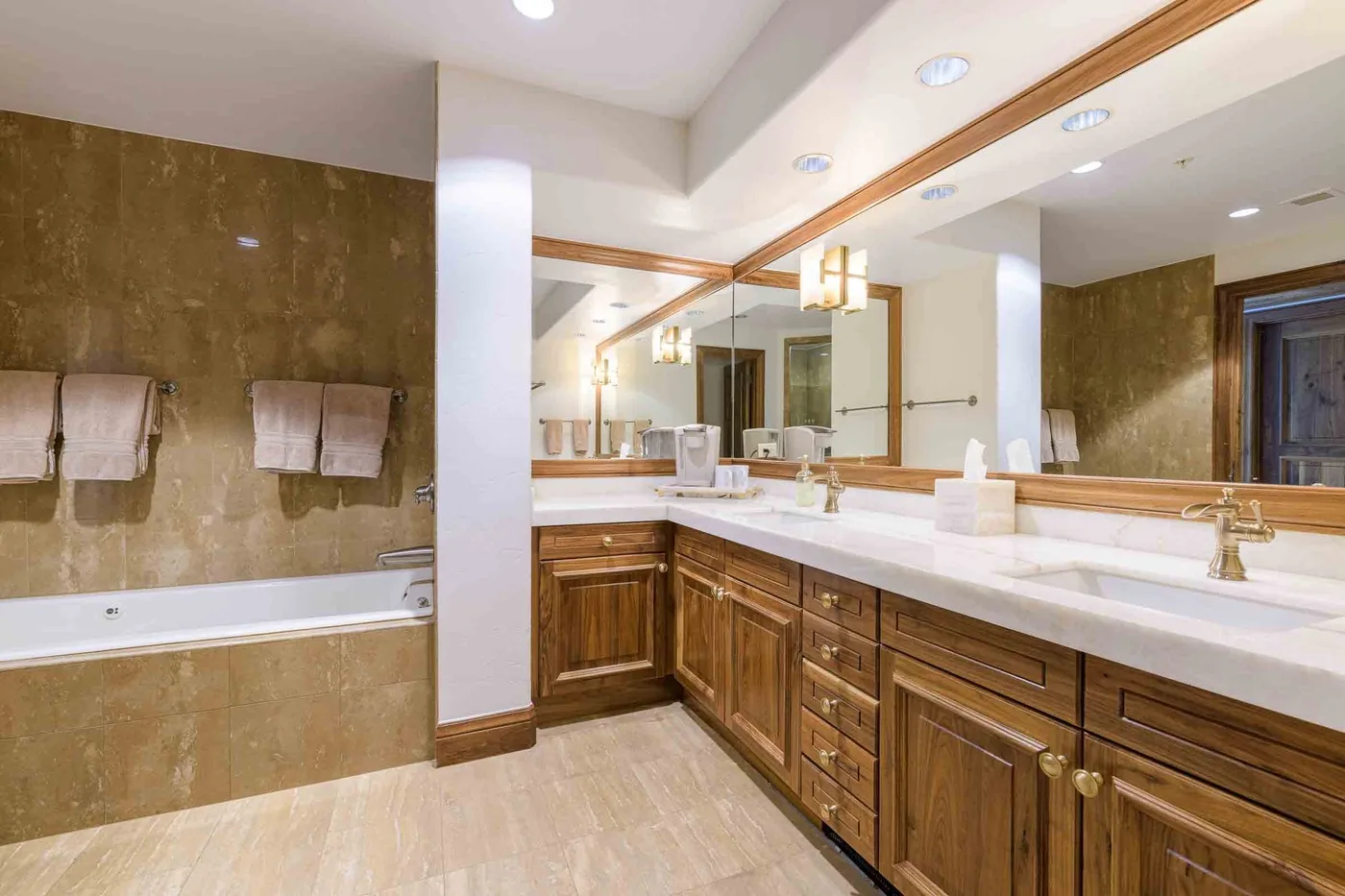 A spacious bathroom with a long vanity, mirrors, and a bathtub.