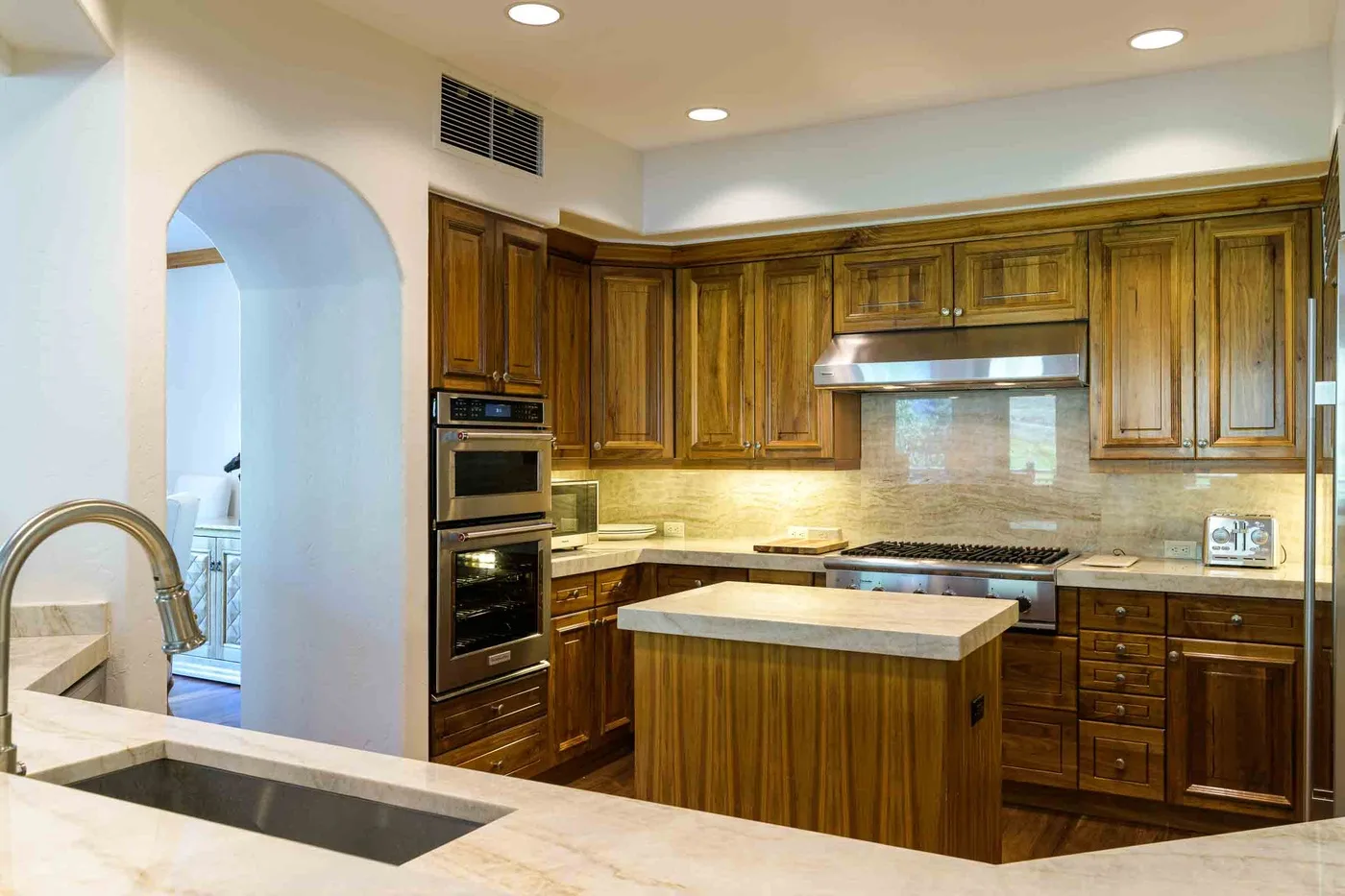 A kitchen with wooden cabinetry, a central island, and built-in appliances.