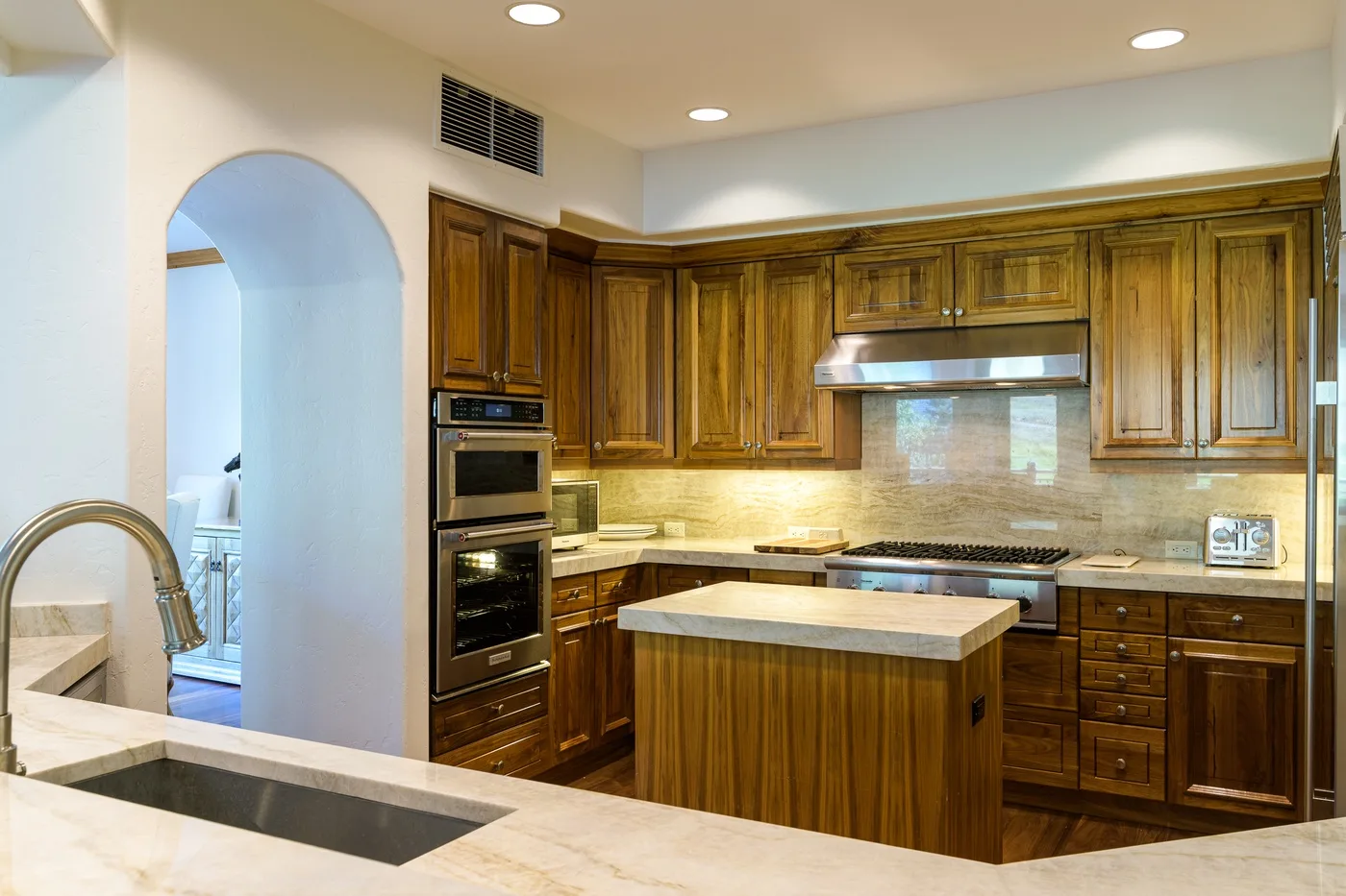 A kitchen with wood cabinetry, a central island, and a sink in the foreground.