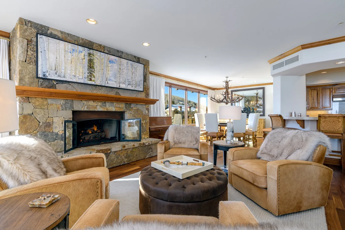 A living room with seating around a coffee table and a stone fireplace.