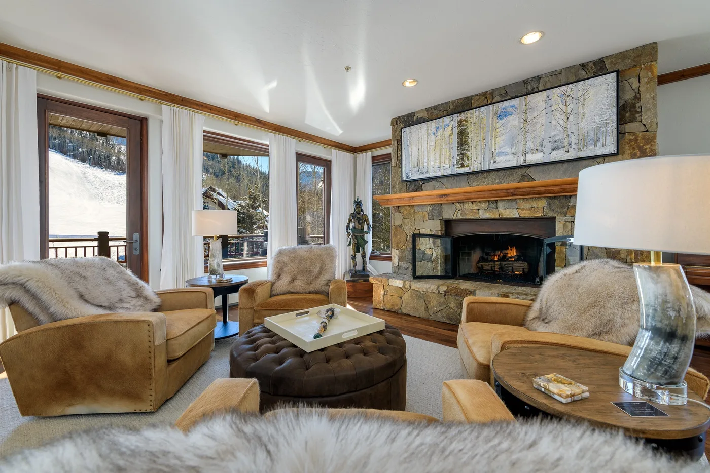A living room with seating arranged around a stone fireplace and coffee table.