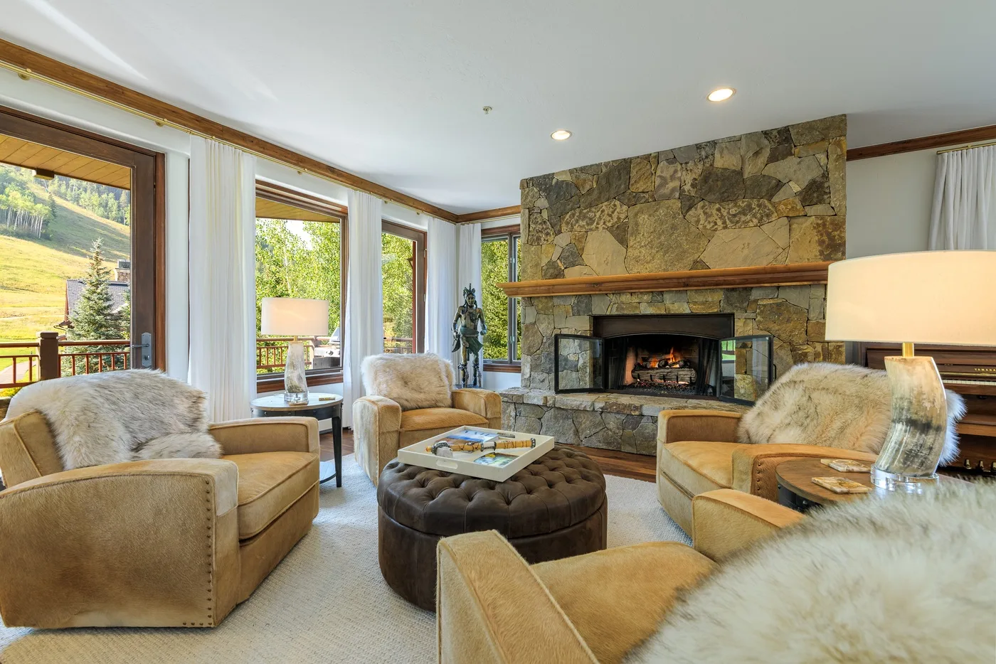 A living room with seating arranged around a stone fireplace and coffee table.