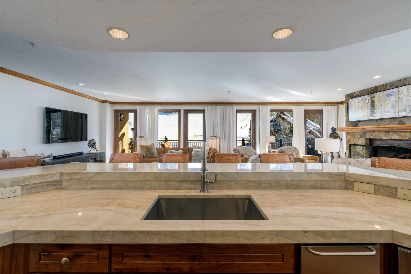 A kitchen island with a sink overlooks an open living and dining area.