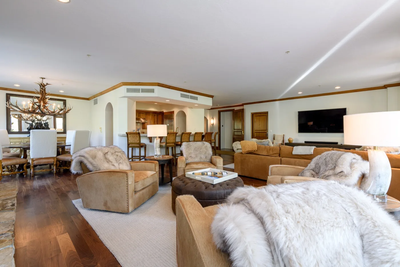 A spacious living room with seating, a dining area, and a wall-mounted television.