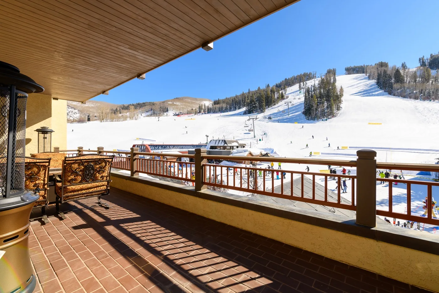 A balcony with outdoor seating overlooks a snowy ski slope.