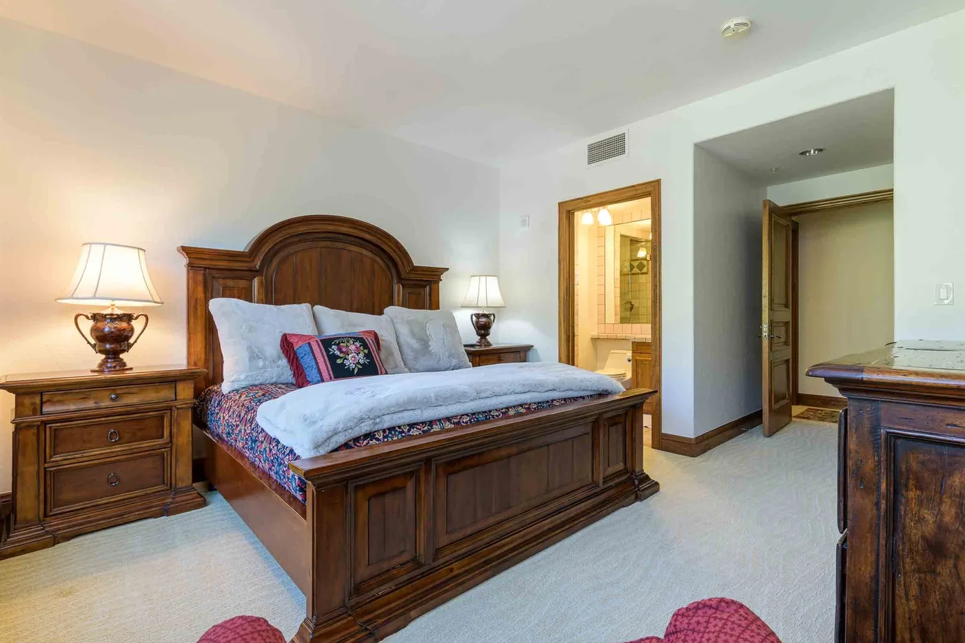 A bedroom with a wooden bed, bedside tables, and an open doorway.