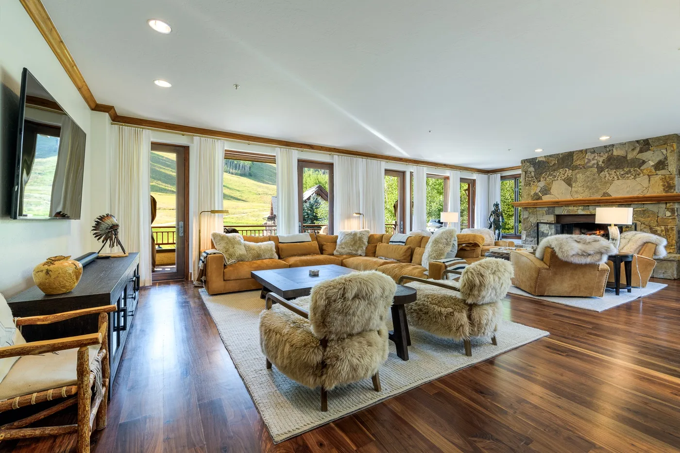 A bright living room with seating around a coffee table and a stone fireplace.