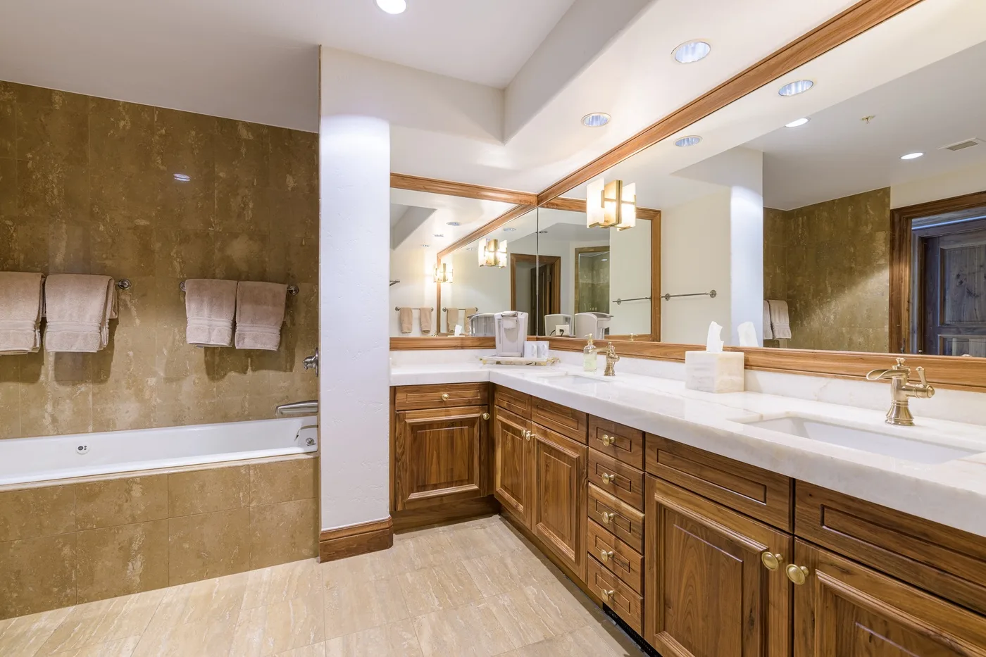 A spacious bathroom with a bathtub, long vanity, and large mirrors.