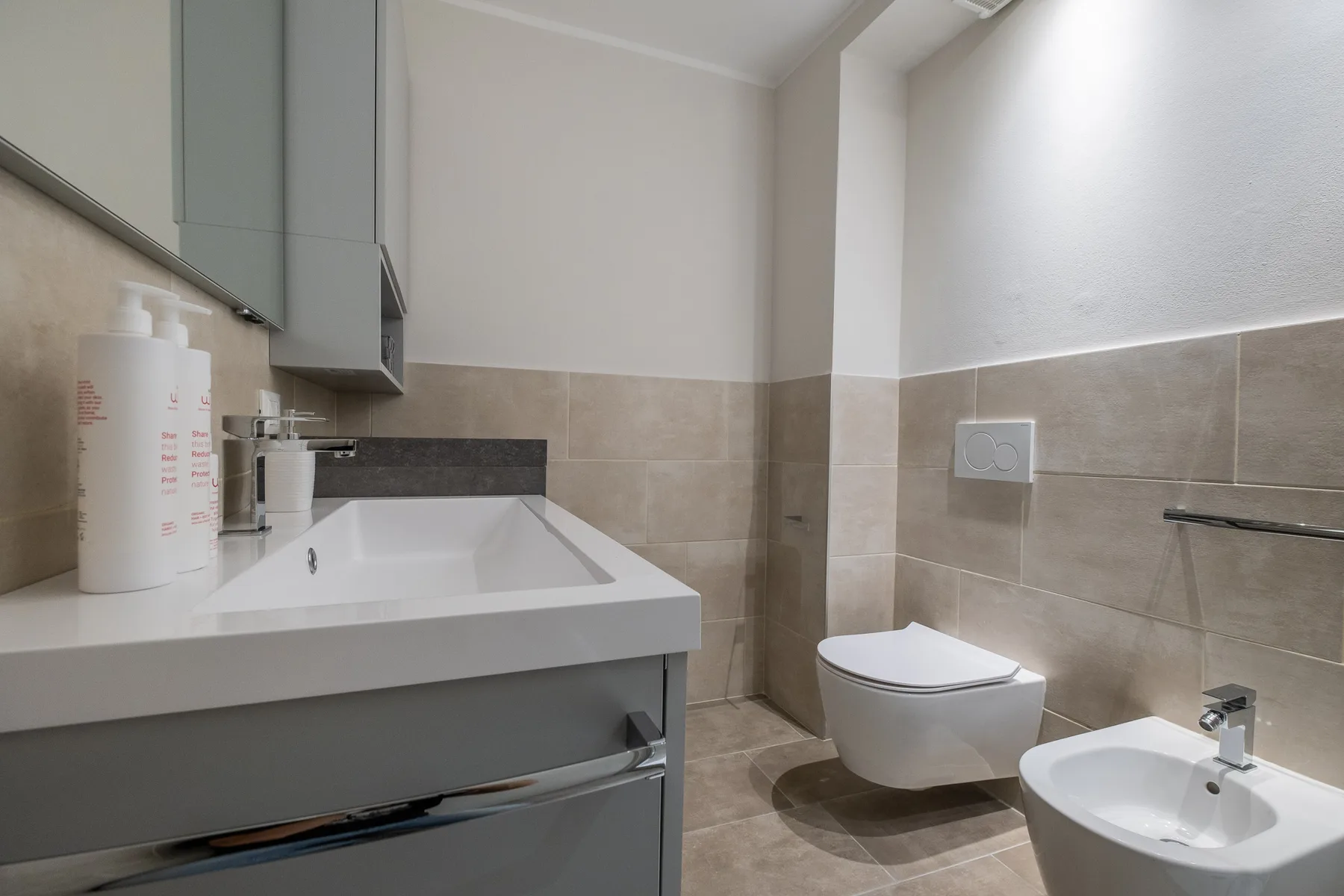 Un baño con tocador, inodoro y lavabo de pared.