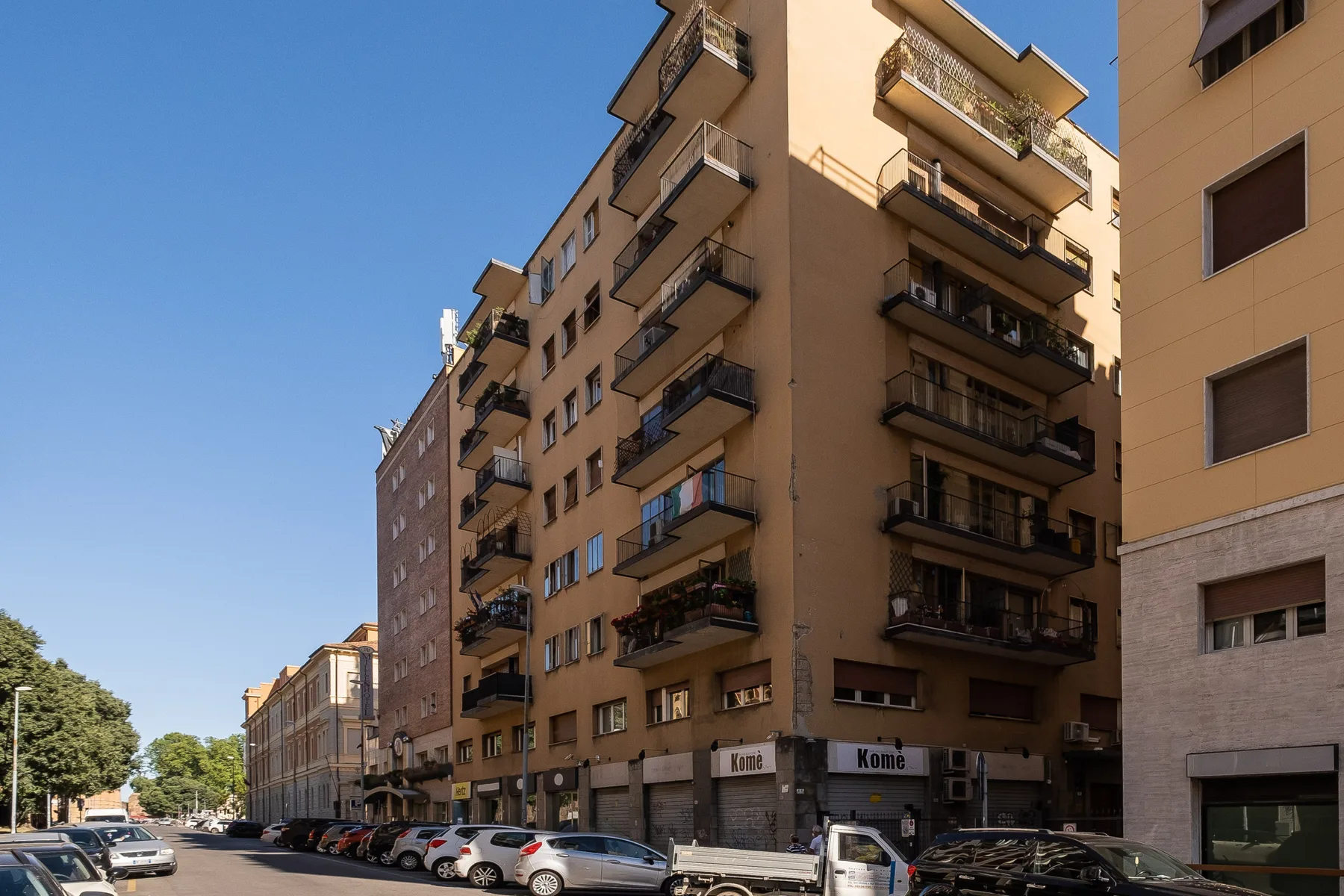 Una calle urbana bordeada de edificios de apartamentos y coches aparcados.