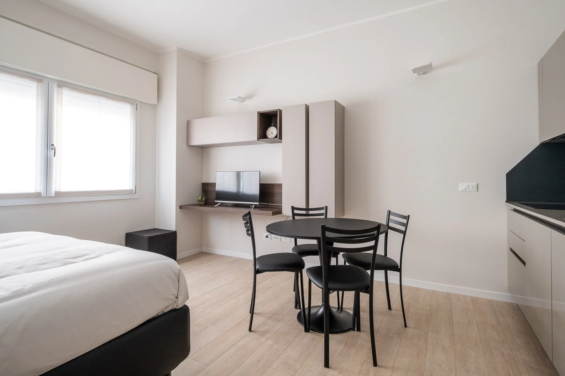 Un dormitorio con una cama, una pequeña mesa de comedor y un televisor.