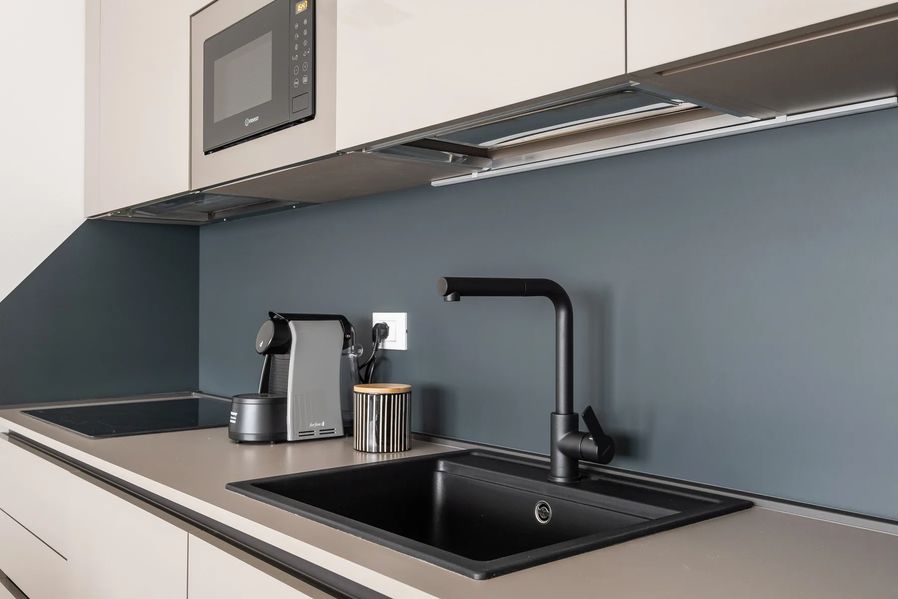 Una encimera de cocina moderna con fregadero, grifo y pequeños electrodomésticos.