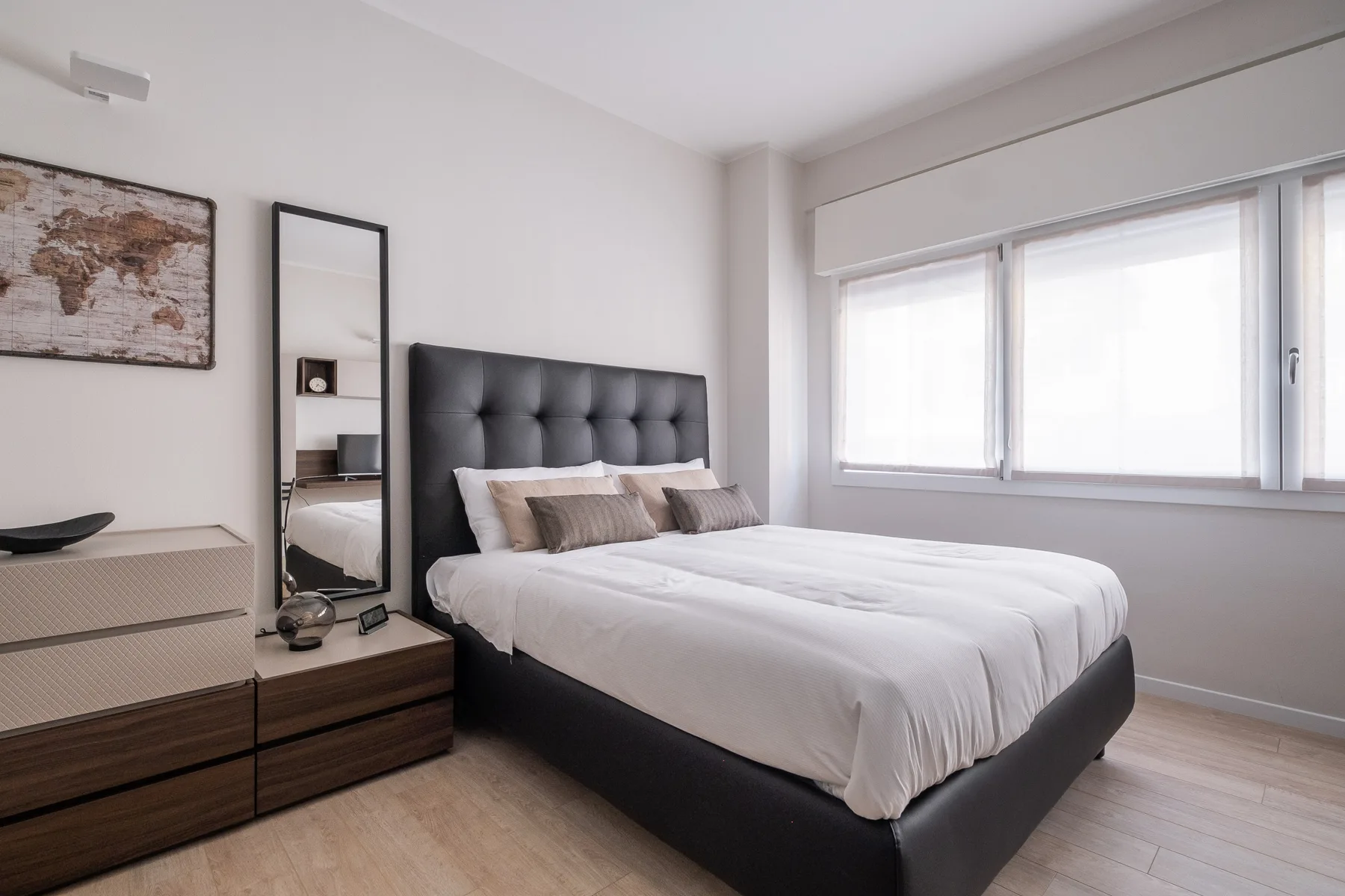 Un dormitorio luminoso con una cama junto a una ventana grande.