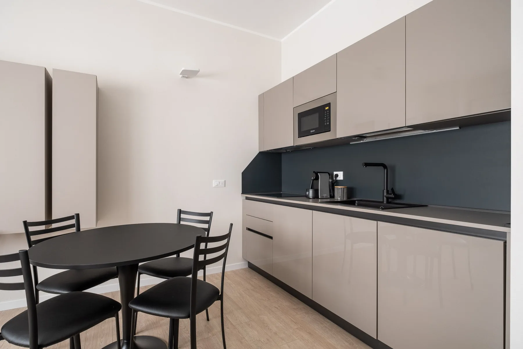 Una cocina moderna y zona de comedor con una mesa y un salpicadero oscuro.