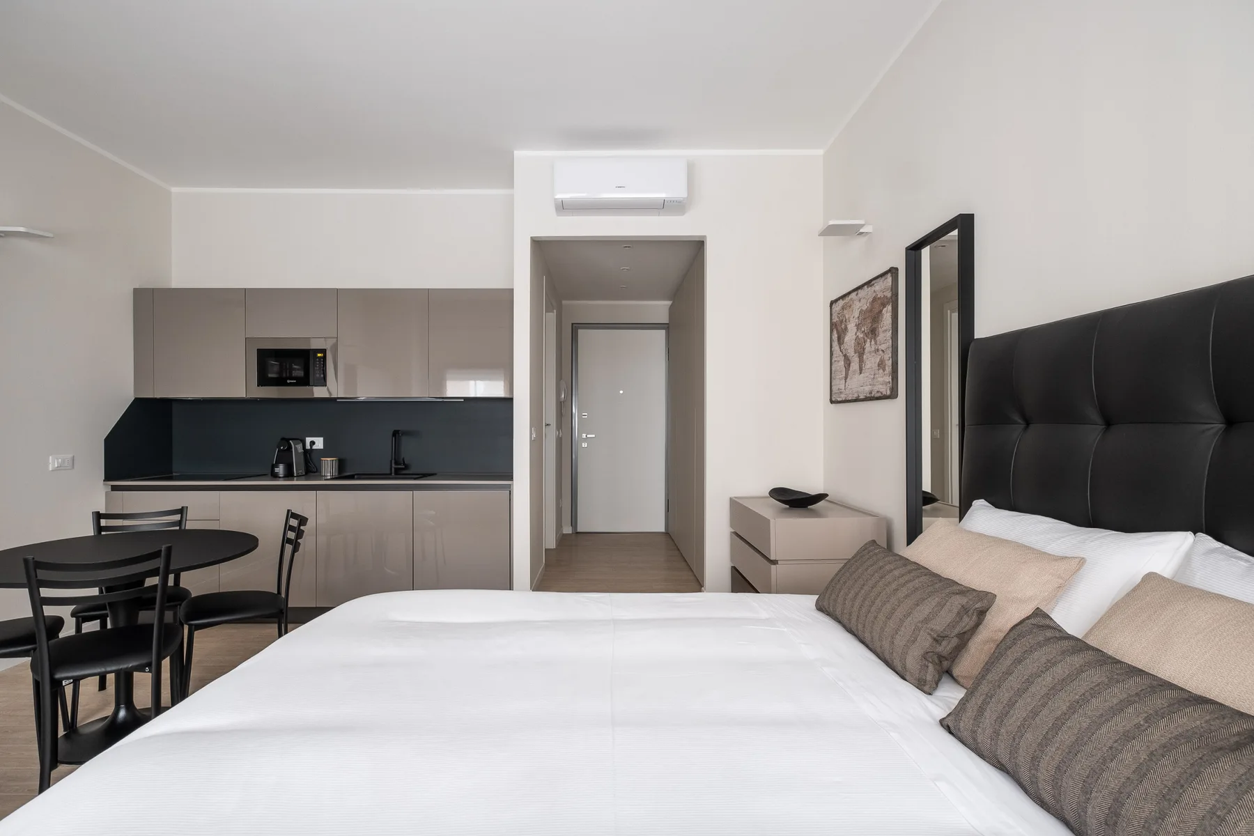 Un dormitorio con una cama grande, junto a una pequeña cocina y una mesa de comedor.