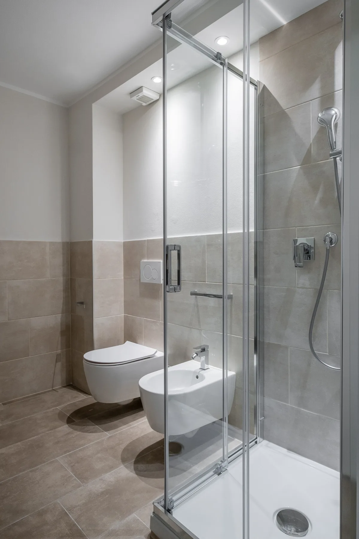 Un baño con ducha de vidrio y accesorios montados en la pared.