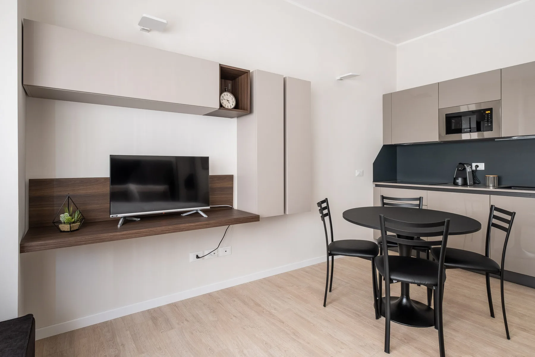 Una pequeña zona de estar y comedor con televisión, mesa y cocina.