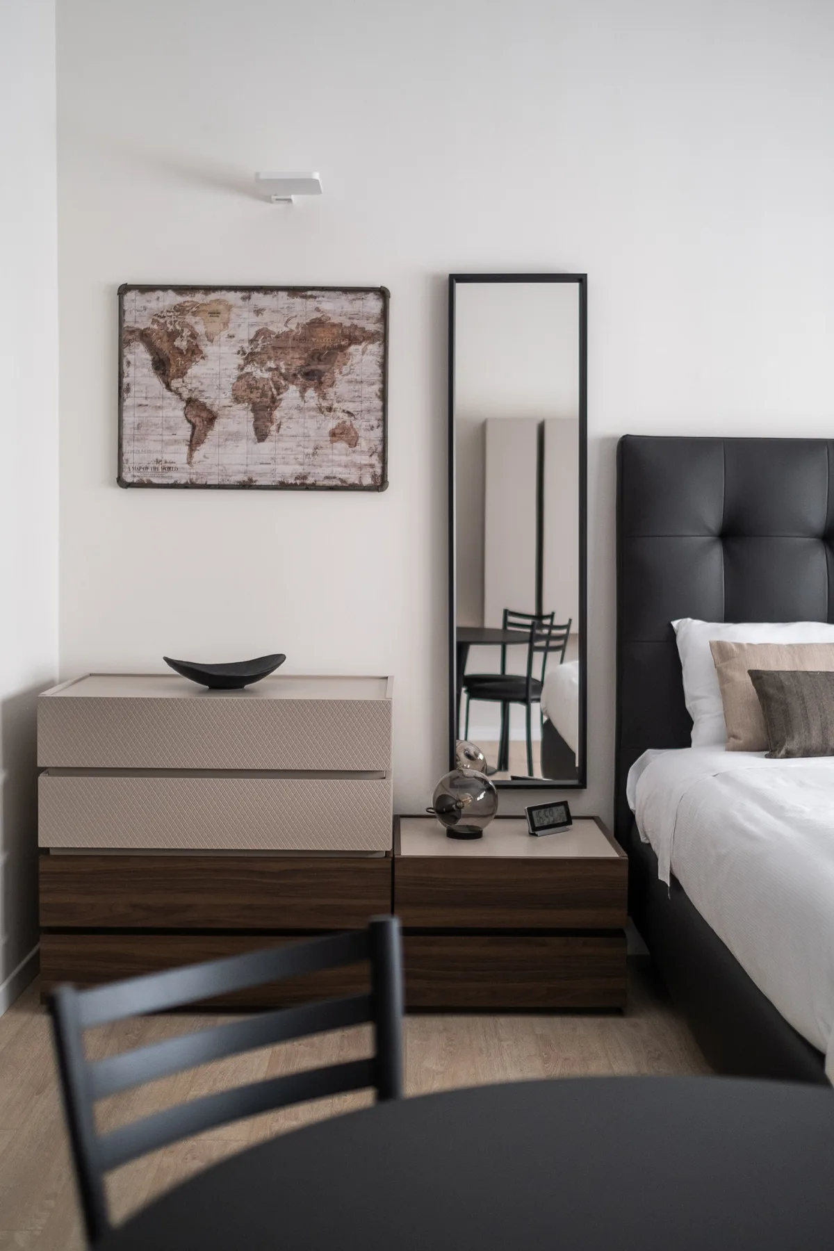Un dormitorio con una cama, mesitas de noche y un mapa del mundo enmarcado.