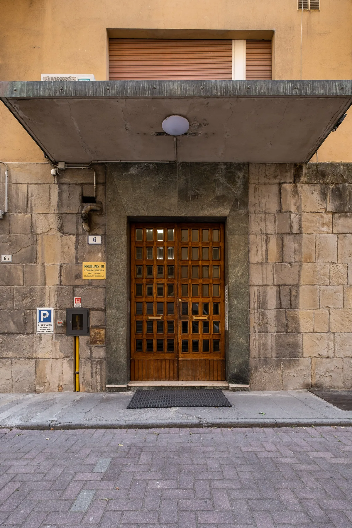Entrada de un edificio a la calle, con una puerta de madera bajo un amplio alero.