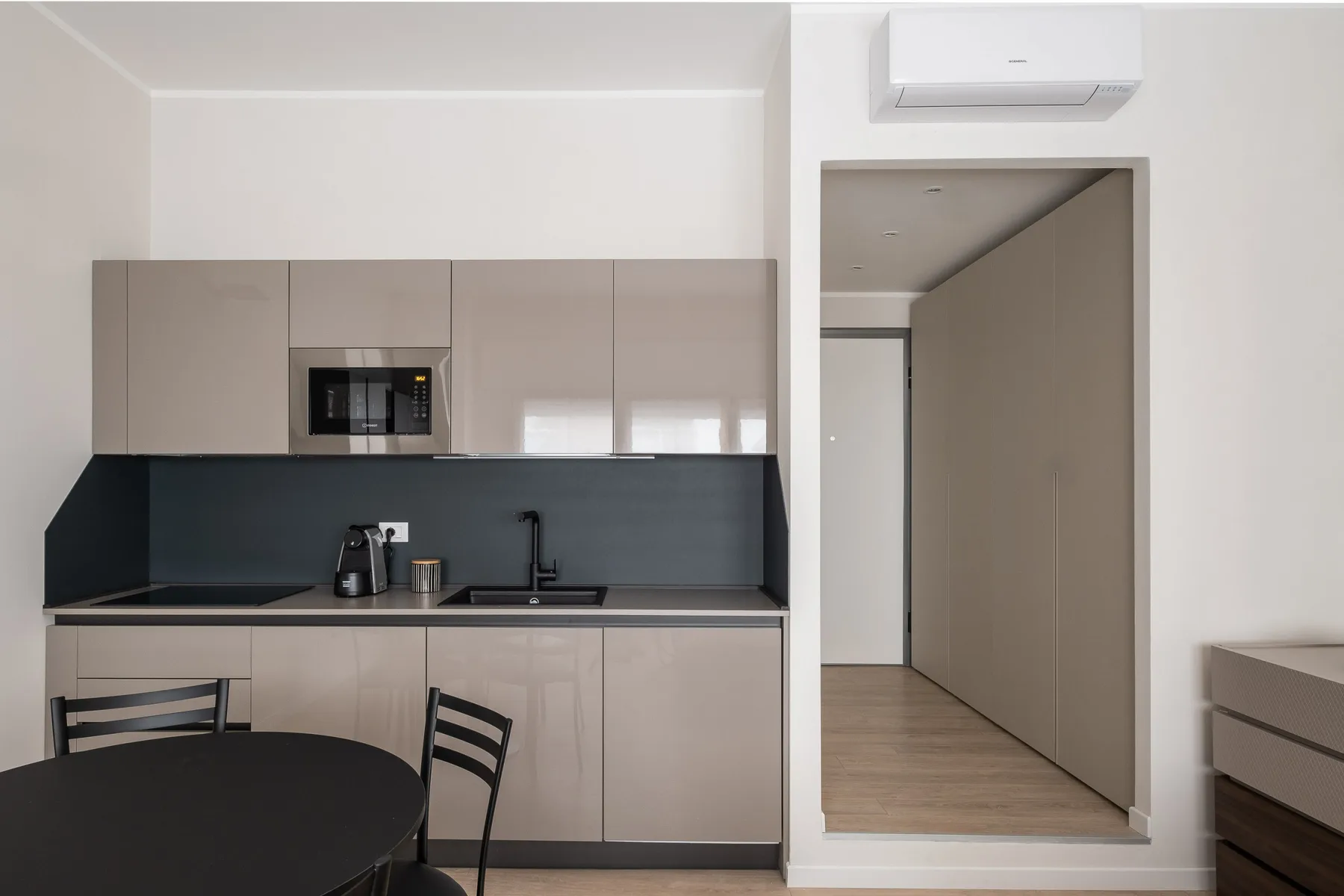 Una cocina moderna con armarios claros, un salpicadero oscuro y una mesa de comedor.