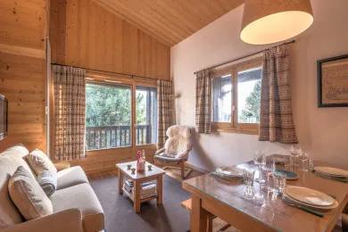 A wood-paneled living and dining area with seating beside large windows.