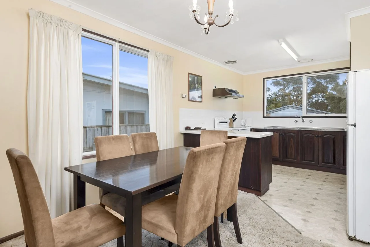 A dining area with upholstered seating beside an open kitchen.