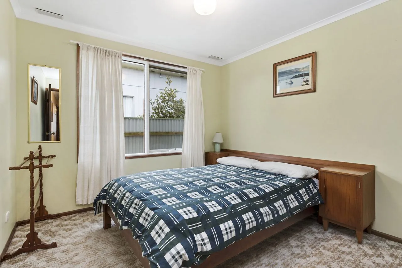 A bedroom with a bed covered by a blue-and-white patterned blanket.