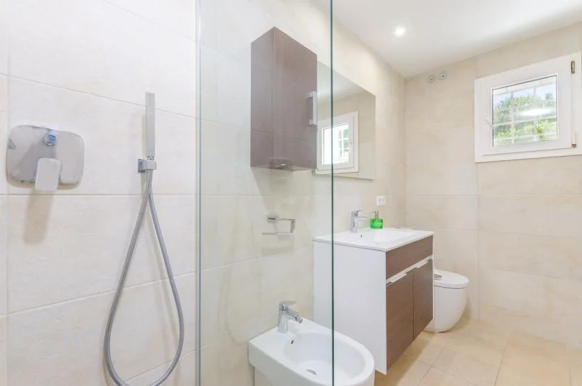 Un baño luminoso con ducha de cristal, lavabo y mueble de baño.