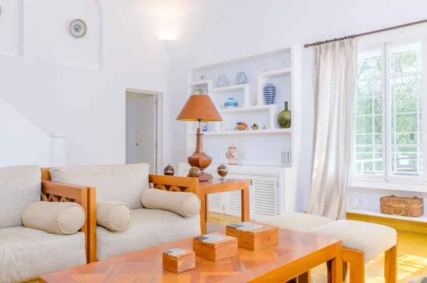 Una sala luminosa con asientos, una mesa de centro de madera y estantes.
