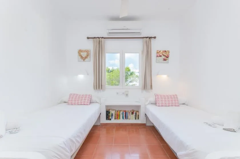 Un dormitorio luminoso con dos camas frente a una ventana.