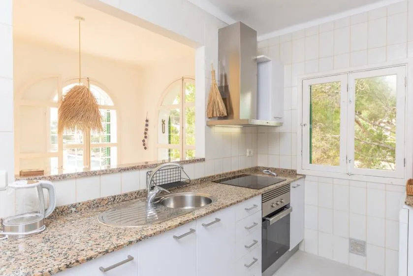 Una cocina luminosa con encimera moteada, fregadero y ventanas.