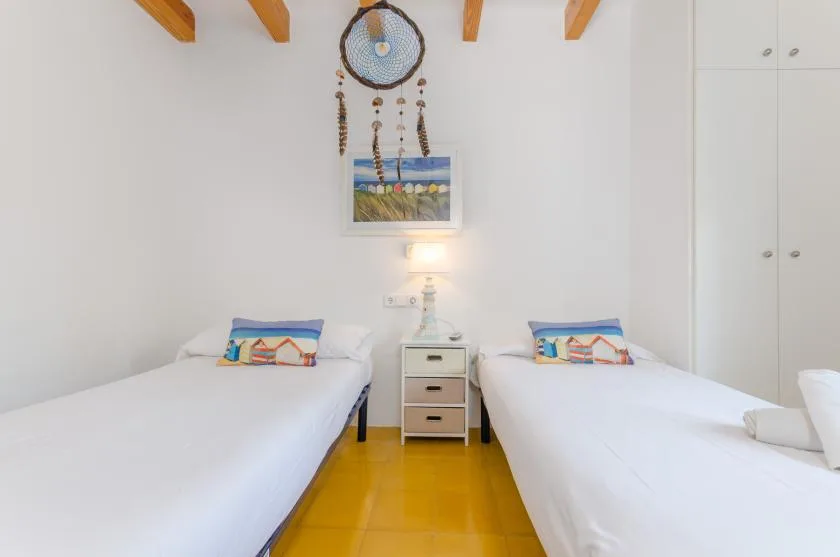 Un dormitorio luminoso con dos camas y una mesita de noche entre ellas.