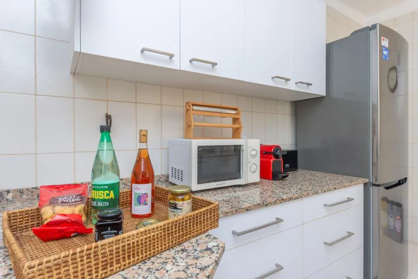 Una encimera de cocina con gabinetes blancos, un microondas y un refrigerador.
