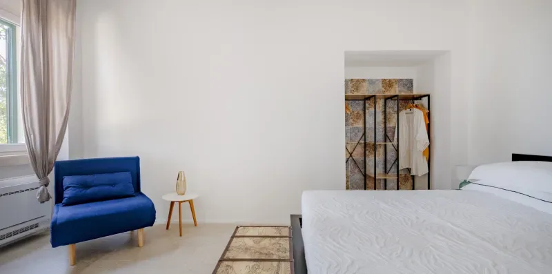 Bedroom with a bed, blue seating, and a small side table.