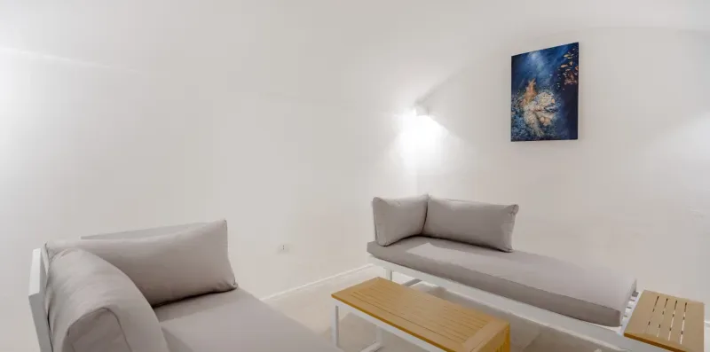 A bright living room with light-colored seating and a small wooden coffee table.
