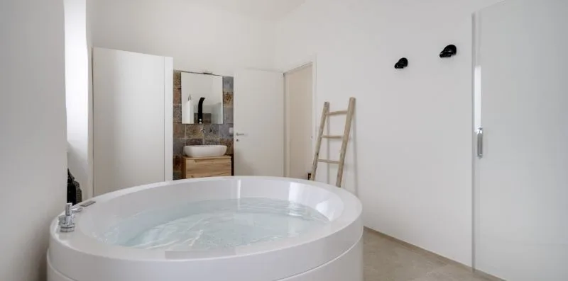 A bathroom features a large round tub and a sink in the background.