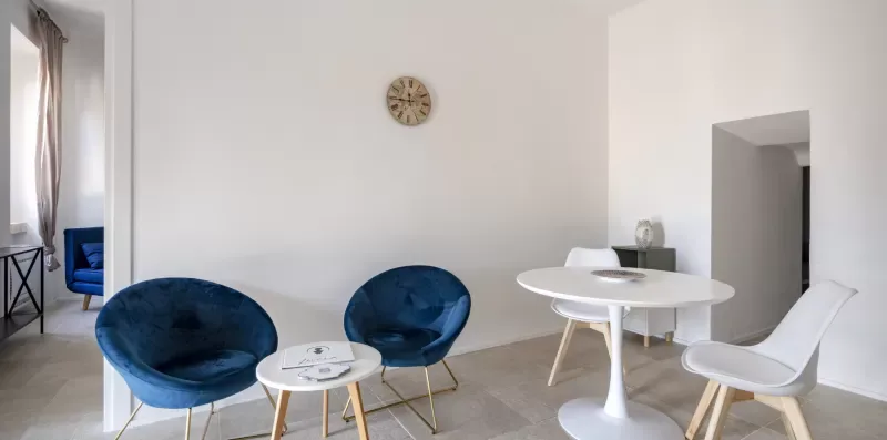A bright dining area with a round white table and blue seating.