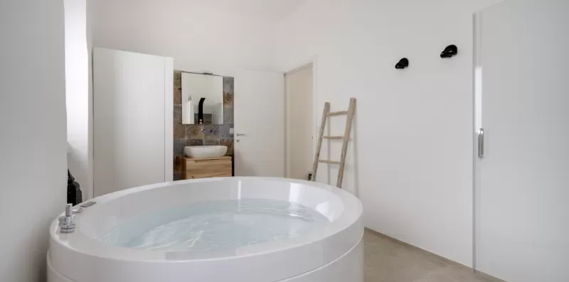 A bathroom with a large round soaking tub and a ladder against the wall.