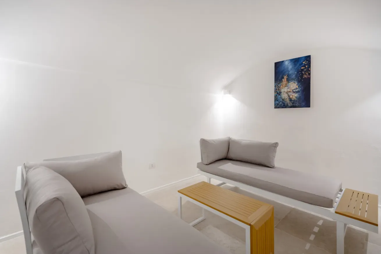 A bright living room with seating, a wooden coffee table, and wall art.